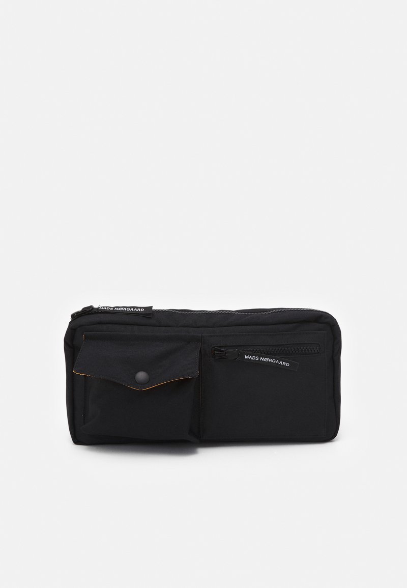 Pochette en toile noire avec un compartiment principal zippé, une poche avant avec un bouton-pression, et une marque sur la fermeture éclair. Coutures orange en accent.