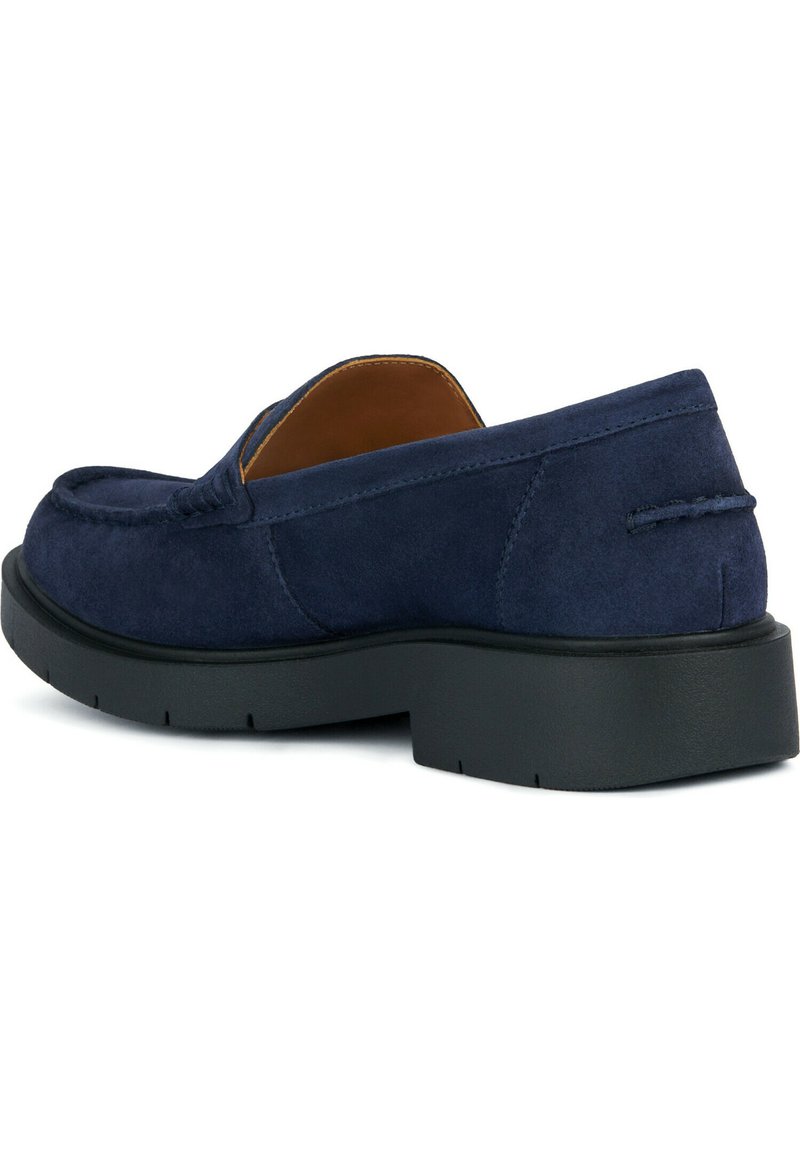 Męskie granatowe zamszowe mokasyny z czarną grubą podeszwą i przeszyciem w stylu mokasynów, widziane z tylnego bocznego kąta.