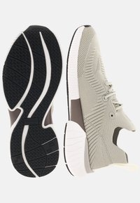 Chaussures de sport gris clair avec une tige en maille texturée, une semelle coussinée et une semelle extérieure en caoutchouc noir présentant un motif de bande de roulement.