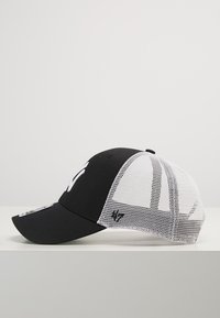Căciulă alb-negru cu un panou frontal solid negru, spate din plasă, bor sub formă de arc și un detaliu cu logo pe partea laterală, având un design structurat.