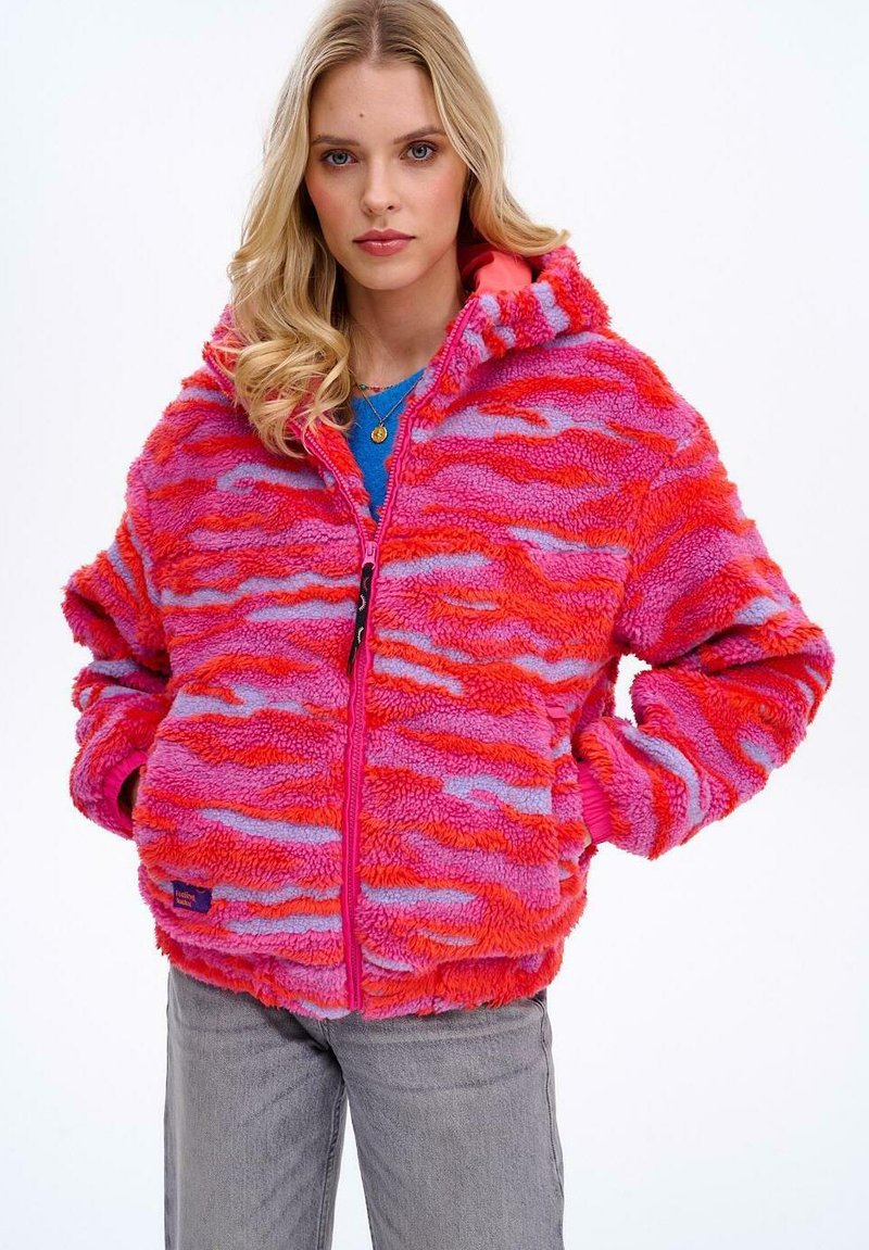 Puchata, kapturowa kurtka z falistym wzorem w odcieniach różu i fioletu, z zamkiem błyskawicznym z przodu i elastycznymi mankietami. Miękka tekstura.
