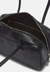 Czarna skórzana torebka z zamkiem błyskawicznym, oferująca przestronną wnętrze i boczną kieszeń. Gładka faktura i minimalistyczny design.