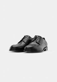 Black leather shoes with a smooth finish, rounded toe, and six eyelet lace-up design; low heel with subtle brand detail on the sole.