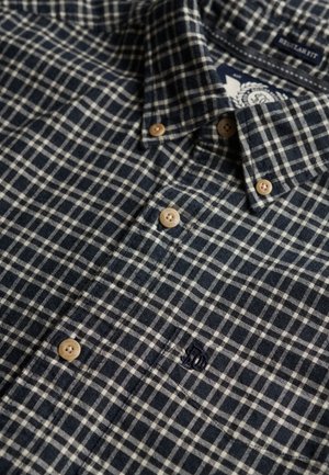 Chemise en coton à carreaux bleu marine et blanc avec col boutonné, boutons en bois et logo brodé sur la poitrine. Design à coupe régulière.