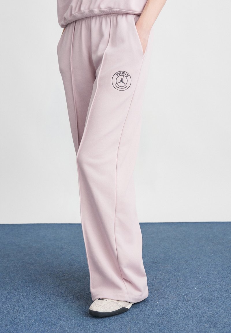 Lyserøde svedbukser med elastisk talje, sidelommer og et cirkulært "Paris" logo på venstre lår. Glat tekstur, loose fit.