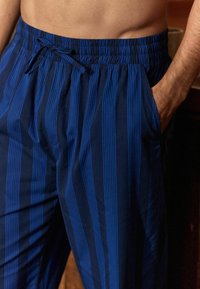 Blauwe gestreepte loungebroek met een elastische tailleband en trekkoord. Twee zijzakken, gemaakt van een soepele, lichte stof.