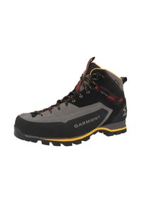Bota de senderismo en negro y gris con suela amarilla y punta de goma negra. Presenta cordones resistentes y soporte reforzado en el tobillo. Marca Garmont visible.
