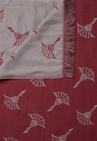 Écharpe en tissu avec un fond bordeaux orné de motifs floraux gris. Fini avec une bordure frangée pour ajouter texture et détails.