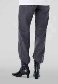 Jean gris foncé avec une coupe légèrement ample, associés à des bottines noires brillantes avec un bout pointu et un petit talon carré.