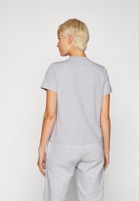 Grå t-shirt med kort ärm, tillverkad av mjuk bomullsblandning, har rund halsringning och en avslappnad passform, visar ryggen och ärmarna.