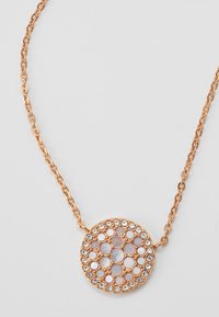 Collana in oro rosa con un pendente circolare dal design a nido d'ape, decorato con cristalli trasparenti e pietre rotonde testurizzate.