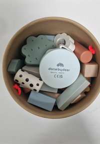 Contenant rond rempli de blocs en bois colorés variés, y compris un en forme d'arbre et une pièce circulaire avec le texte "donebydeer".