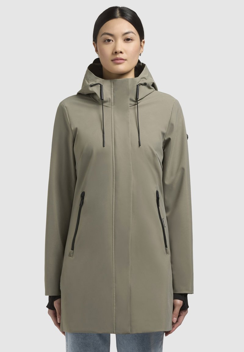 Giacca a vento resistente all'acqua di colore verde oliva, con una vestibilità slim, maniche lunghe, due tasche laterali con zip e cordini regolabili.