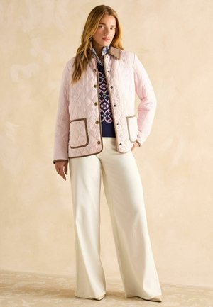 Quilted pink jacket with brown accents and two front pockets, paired with white wide-leg pants and a navy patterned sweater underneath.