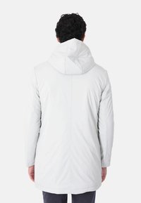 Giubbotto isolante bianco con cappuccio, caratterizzato da una trama liscia e un taglio allungato. Cappuccio regolabile e cuciture visibili sul retro.