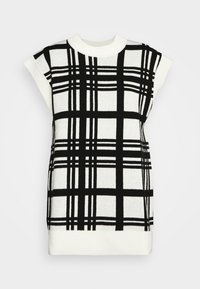 Haut sans manches en maille noir et blanc avec un col montant, présentant un motif à carreaux audacieux et des poignets en côtes. Le matériau a une texture douce.