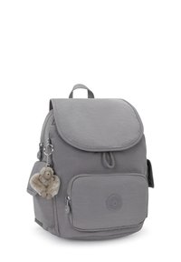 Sac à dos en tissu gris avec une fermeture à rabat, une poche zippée à l'avant, une poche en maille sur le côté et un accent en fourrure. Comprend des sangles rembourrées et une poignée supérieure.