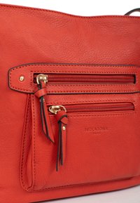 Borsa a mano in pelle rossa con finitura testurizzata, dotata di due tasche con cerniera, dettagli in metallo dorato e logo impresso sul fronte.