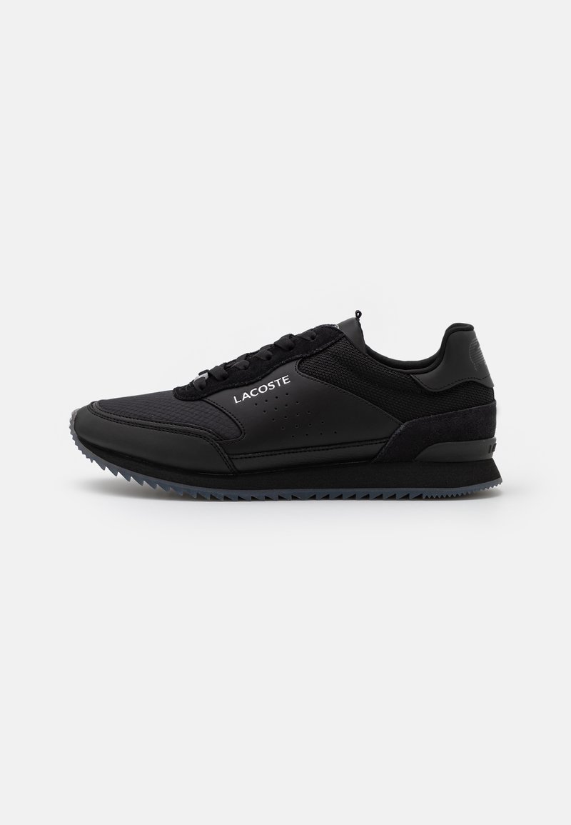Baskets basses noires Lacoste avec panneaux en mesh et cuir, fermeture à lacets et semelle texturée, vues de côté sur fond blanc.