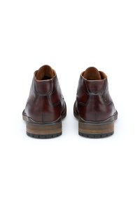 Mørkebrune læderankelstøvler med en glat finish, rund tå og kontrasterende lysebrune indersåler. Har en robust gummisål og diskret syning.