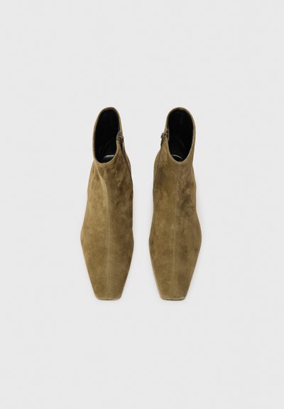 Botines de ante verde oliva con diseño de punta afilada, cierre de cremallera en el costado y forro interior suave. Textura suave y silueta elegante.