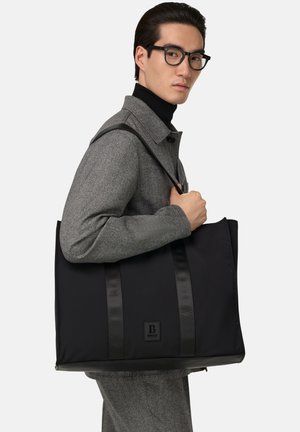Borsa a tracolla nera con strisce in satin, realizzata in materiale resistente. Presenta una patch con logo, una forma strutturata e un design elegante e minimalista.