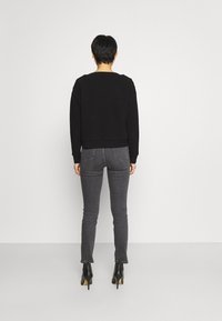 Svart cropped tröja med långa ärmar, ribbade ärmslut och fåll, tillsammans med mörkgrå slim fit-jeans och svarta högklackade ankelstövlar.