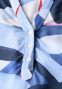Camicia con bottoni e scollo a V, realizzata in tessuto morbido con motivi astratti nei toni del blu, blu navy, rosso e rosa.