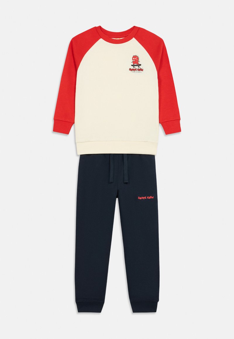 Svet outfit i bomuld med en cremefarvet top med røde raglanærmer og grafik, parret med navy joggers. Inkluderer elastisk talje.