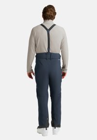 Pantaloni da sci impermeabili blu navy con spalline regolabili, tasche con zip e design a gamba affusolata; realizzati in materiale resistente e elastico.