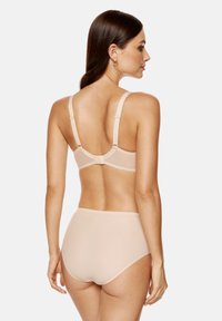 Zestaw biustonosza i majtek w kolorze nude, wykonany z miękkiego, gładkiego materiału, z regulowanymi ramionkami oraz bezszwowym wykończeniem z falbaniastymi brzegami.