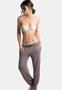 Soutien-gorge sans bretelles beige avec des détails subtils, associé à un pantalon de détente ample en marron clair avec une taille élastique et des poches latérales.