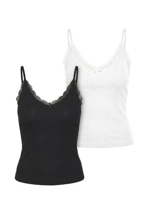 Kvinde iført mørke solbriller, sort ærmeløs top, løse, falmede jeans med bælte, sorte sandaler og bærende en sort skuldertaske.