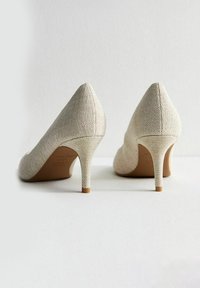 Scarpe con tacco alto beige texturizzate, dal design a punta, con un tacco sottile e una fodera interna liscia.