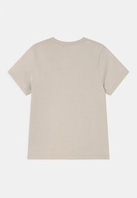 Vaaleanbeige puuvillapaita lyhyillä hihoilla, pyöreällä kaula-aukolla, nähtynä takaa valkoista taustaa vasten.