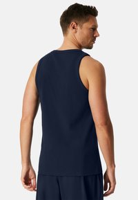 Navy blauwe mouwloze tanktop met een klassiek ronde hals en een rechte zoom. Glad materiaal, minimalistische stikseldetails en een casual pasvorm.