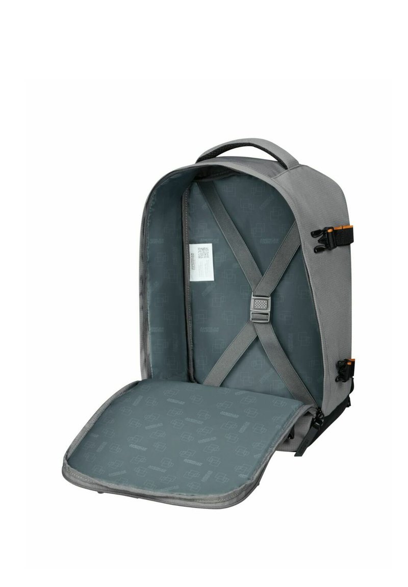 Grå ryggsäck med en strukturerad design, med justerbara axelremmar, ett interiör med mönstrad foder, och en säker framklaff.