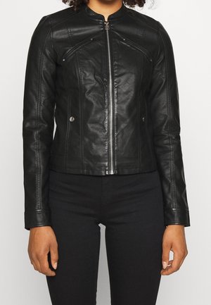 Czarna dopasowana skórzana kurtka z przednim zamkiem błyskawicznym, kieszeniami na piersi zamykanymi na zamek oraz kieszeniami bocznymi zapinanymi na zatrzaski, noszona z czarnymi spodniami.