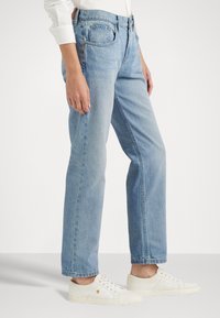 Lichtblauwe denim jeans met een rechte pasvorm, voorzien van een hoge taille, een vijf-pocket ontwerp en witte sneakers.