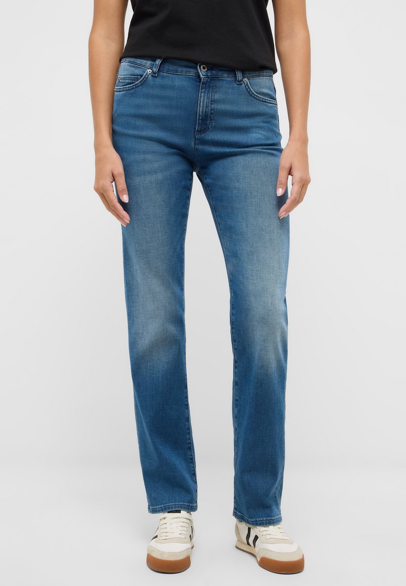 Zilas džinsa bikses ar taisnu kāju piegriezumu, priekšpusē ir kabatas un izbalējis mazgājums. Kombinētas ar neitrālām kedām.