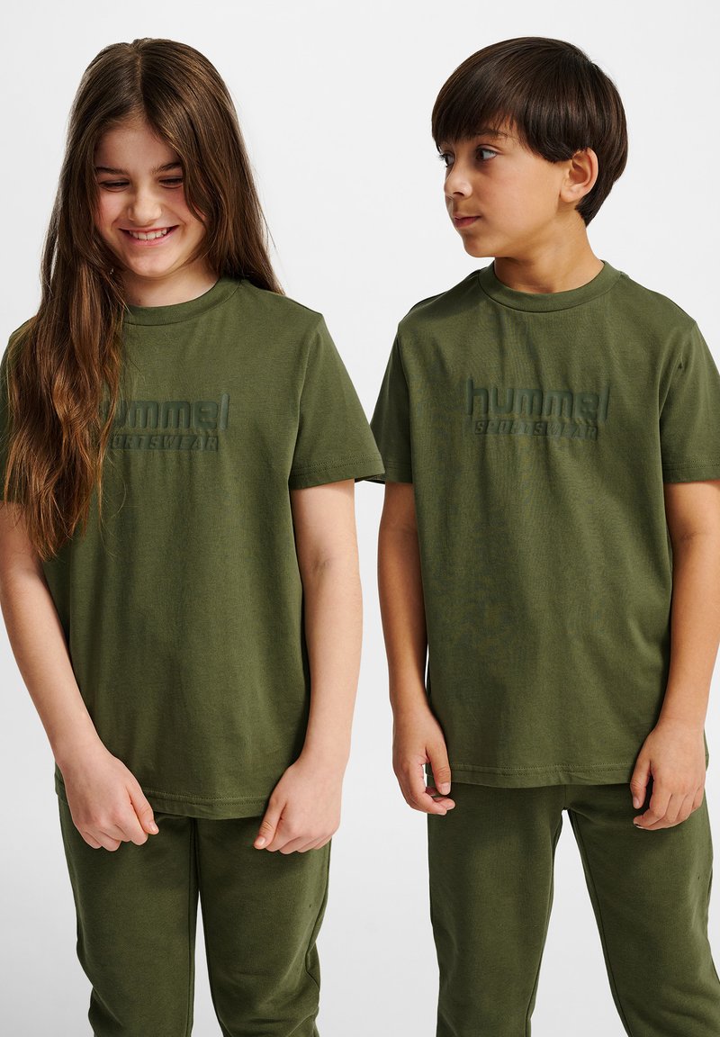 Oliwkowe bawełniane t-shirty z krótkim rękawem, ozdobione teksturowanym logo, w połączeniu z pasującymi oliwkowymi spodniami o luźnym kroju.