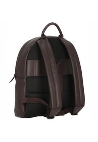 Mochila de cuero marrón con respaldo de malla acolchada, correas ajustables y un asa superior. Diseño elegante y construcción robusta.