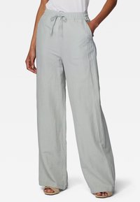 Lichtgrijze, wijde broek met een elastische tailleband en verstelbaar trekkoord. Gemaakt van een zachte, lichte stof. Functionele zijzakken.