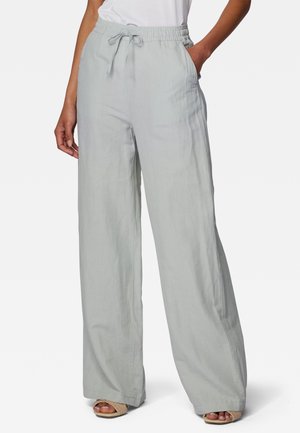 Pantalones de pierna ancha en color gris claro, con cintura elástica y cordón ajustable. Fabricados con una tela suave y ligera. Con bolsillos laterales funcionales.