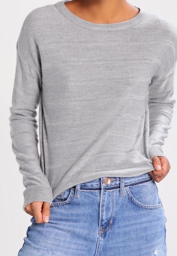Pull à manches longues gris clair avec de fines rayures horizontales, porté sans être rentré dans un jean bleu de lavage moyen.