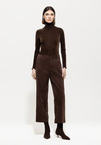 Brown velvet turtleneck top paired with wide-leg brown corduroy pants. The outfit features long sleeves and pointed ankle boots.