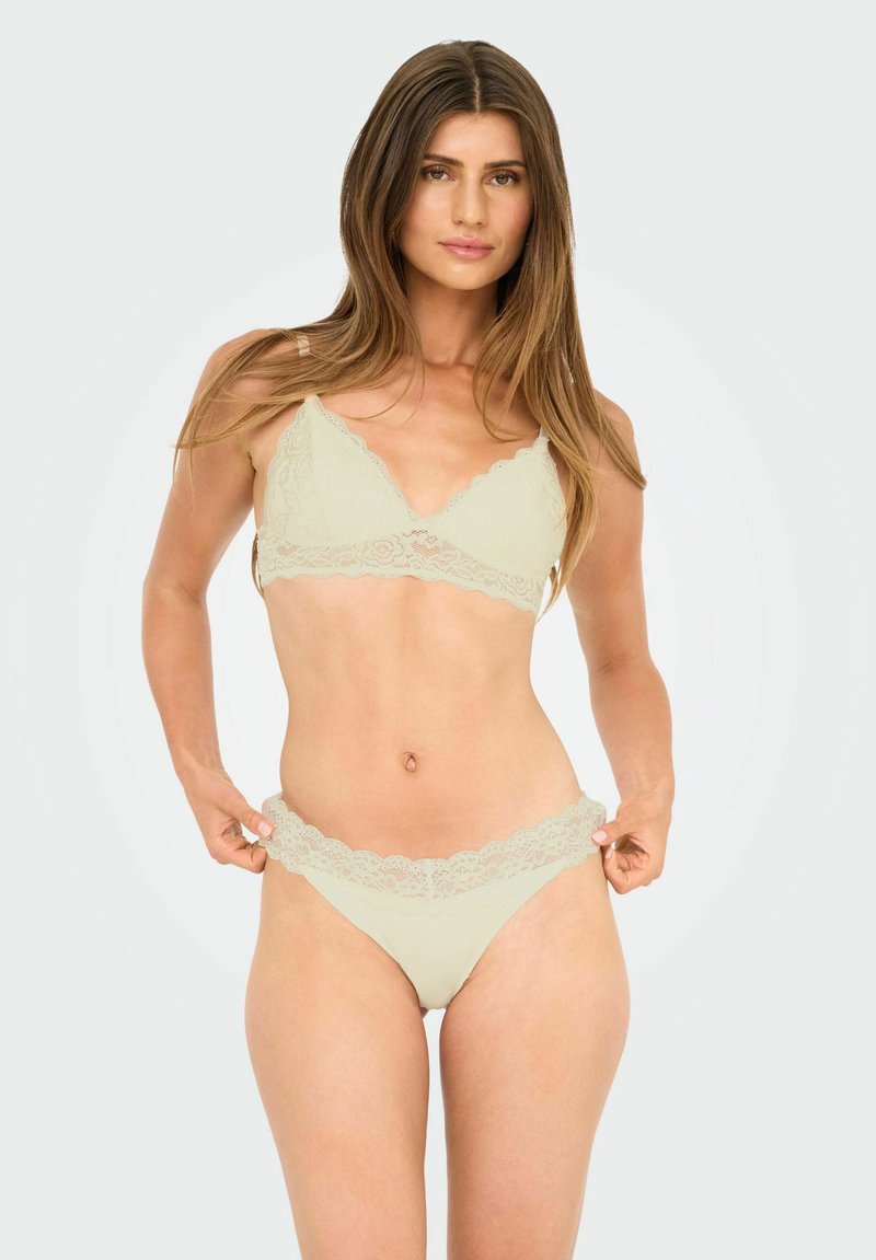 Light green lace bra and matching thong with scalloped edges. The fabric is soft with intricate lace detailing on the band.