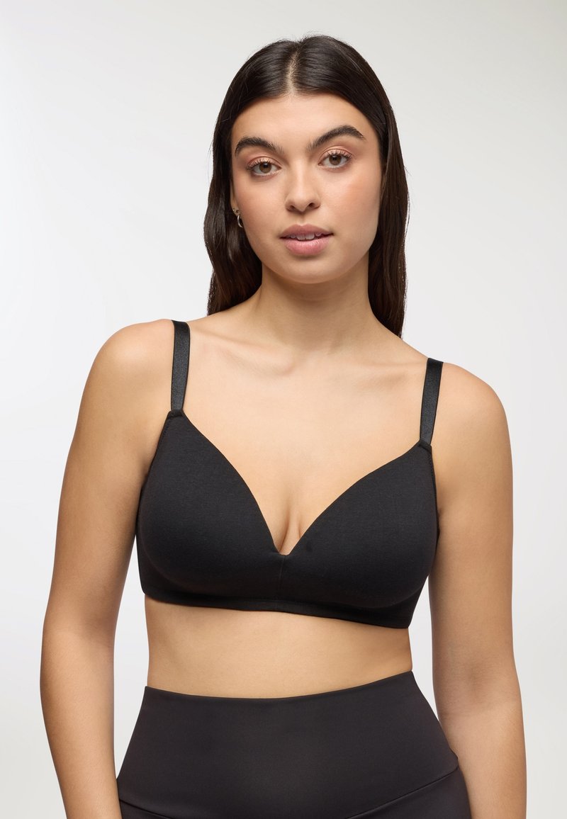 Reggiseno nero senza cuciture con scollatura profonda, spalline sottili e una texture morbida e liscia. Nessuna ferramenta visibile o imbottitura.