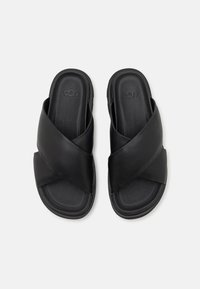 Černé kožené nazouvací sandály s designem křížových pásků a texturovanou stélkou. Hladké povrchy s formovanou podešví pro pohodlí.