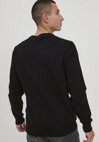 Schwarzer Pullover, lange Ärmel, gerippte Bündchen und Saum, Rundhalsausschnitt, Baumwollmischung, glatte Textur, minimalistisches Design ohne sichtbare Logos.